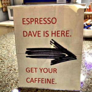 Office sign in lucite frame on a counter saying that "Espresso Dave is here."