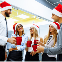 Work group at holiday office party with santa hats and red coffee mugs