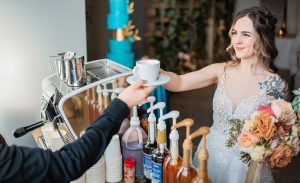 Espresso Dave barista in black shirt handing a cappuccino to a smiling bride with bouquet Capture the North Photography