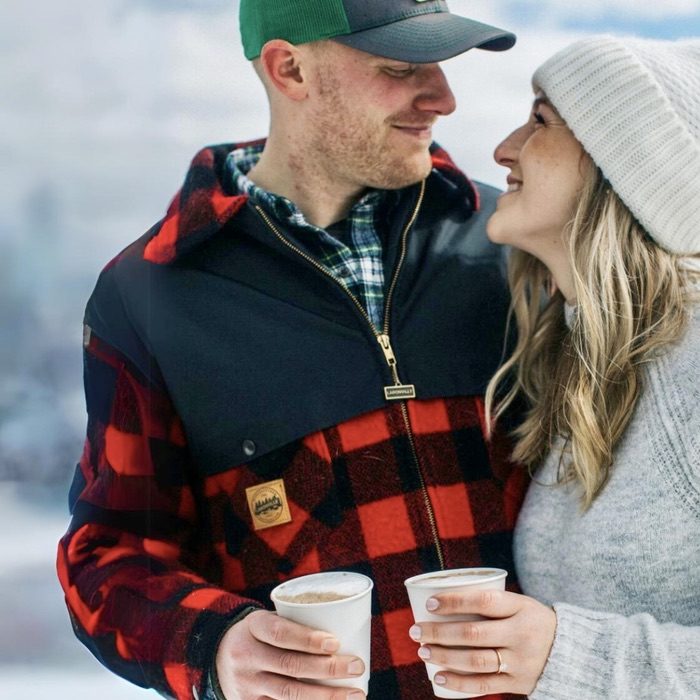 Couple staring into each others eyes dressed in outdoor winter clothing holding onto cups of hot lattes