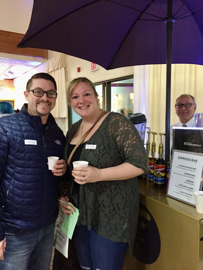 Engaged Couple drinking coffee in front of coffee cart and barista at Wedding Show